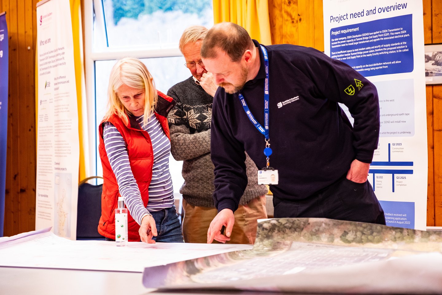 Members of the public and an SSEN Transmission employee examining maps on a table.