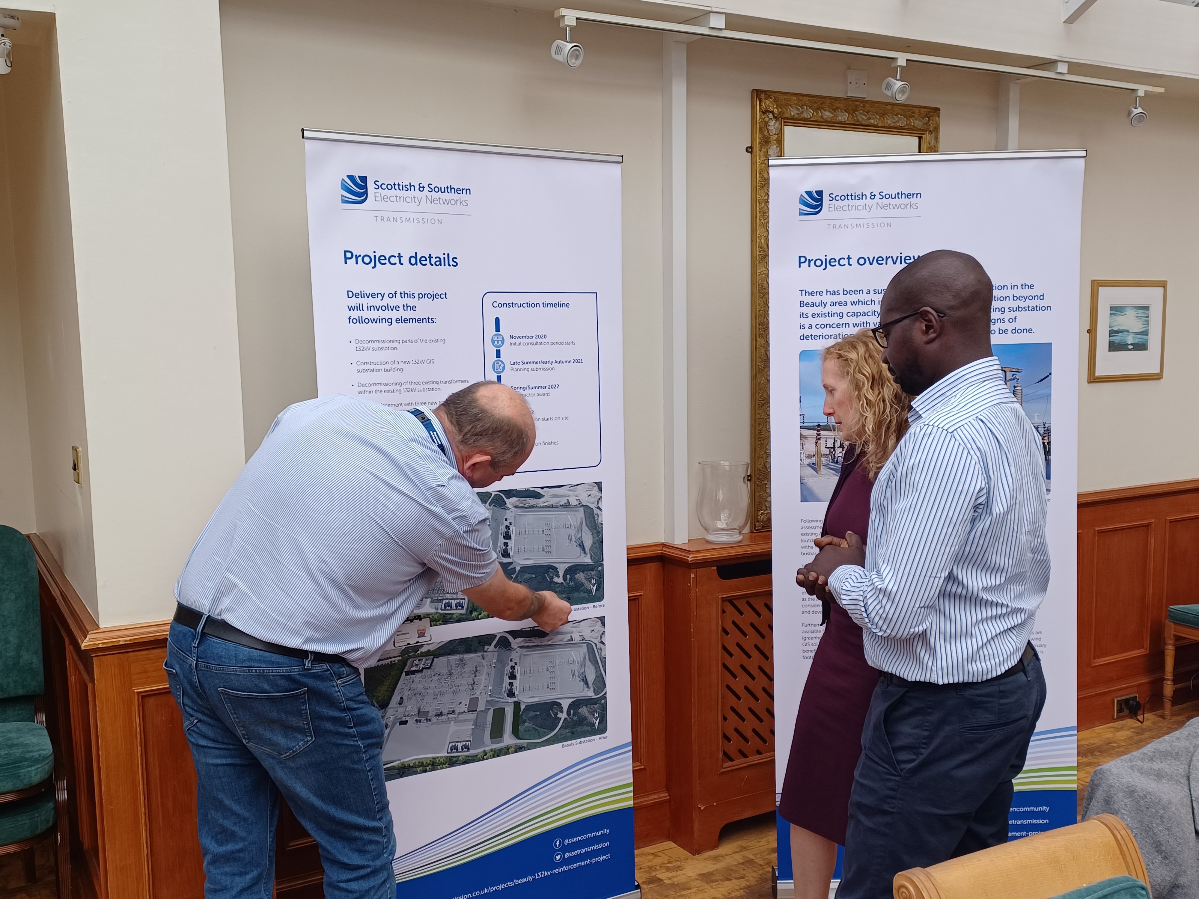 An SSEN Transmission employee and members of the public examining project posters.