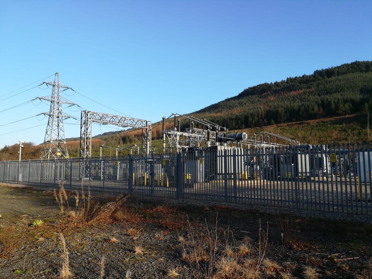 A substation enclosed by a metal fence.