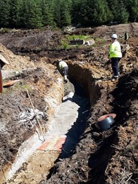 A contractor in PPE in an excavated trench.