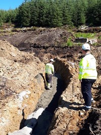 A contractor in PPE in an excavated trench.