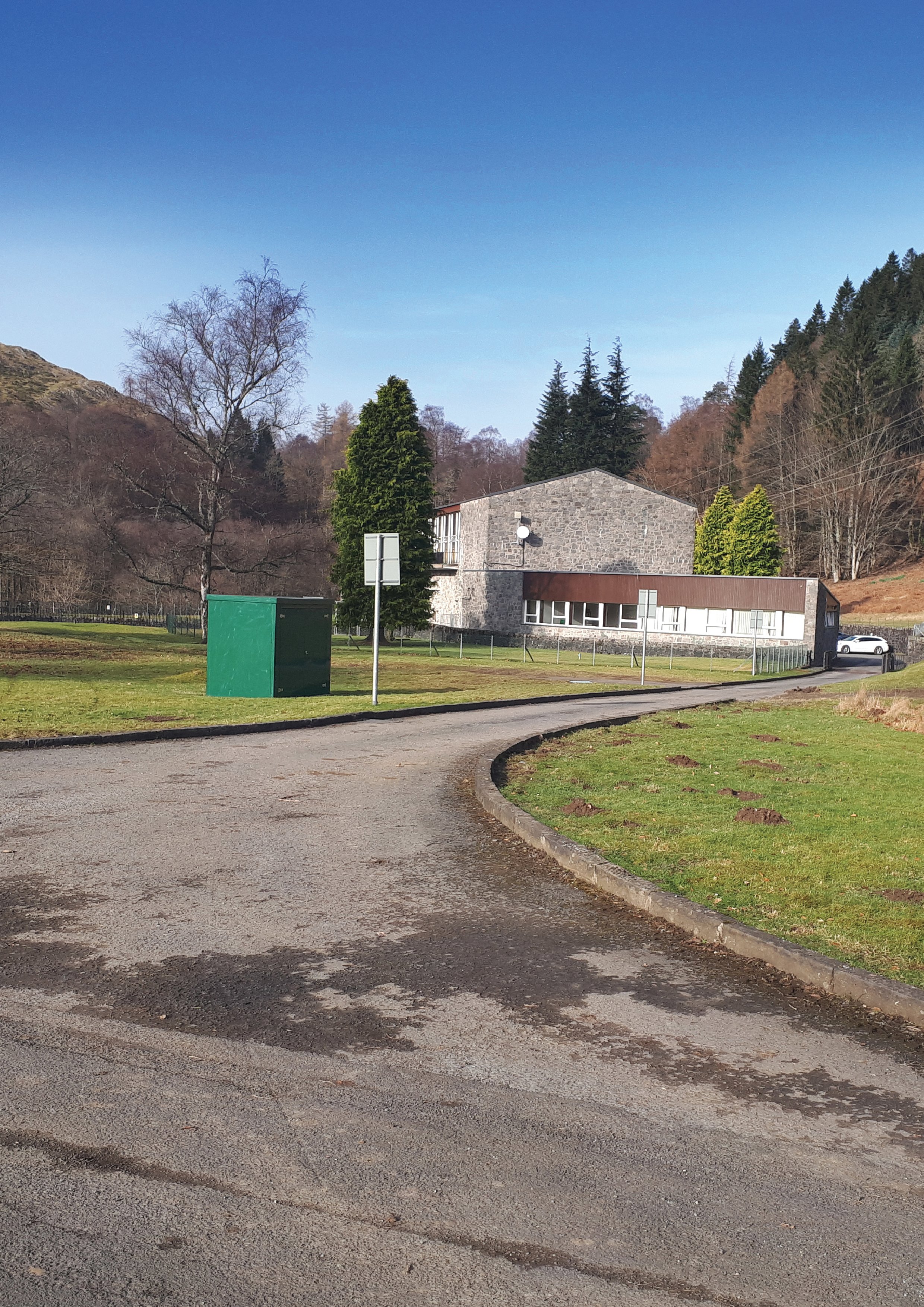 A view from an access road of a stone building.