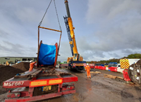 A large cylinder suspended from a crane arm.