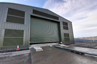 A large metal rolling door on a green metal building.