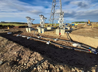 Black cables leading up to metal and concrete transmission structures.