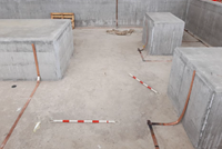 A concrete area, several concrete blocks emerge from this area to which metal sections are attached.