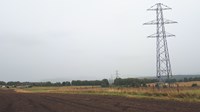Metal transmission towers on a misty day. There are no overhead lines connecting them.